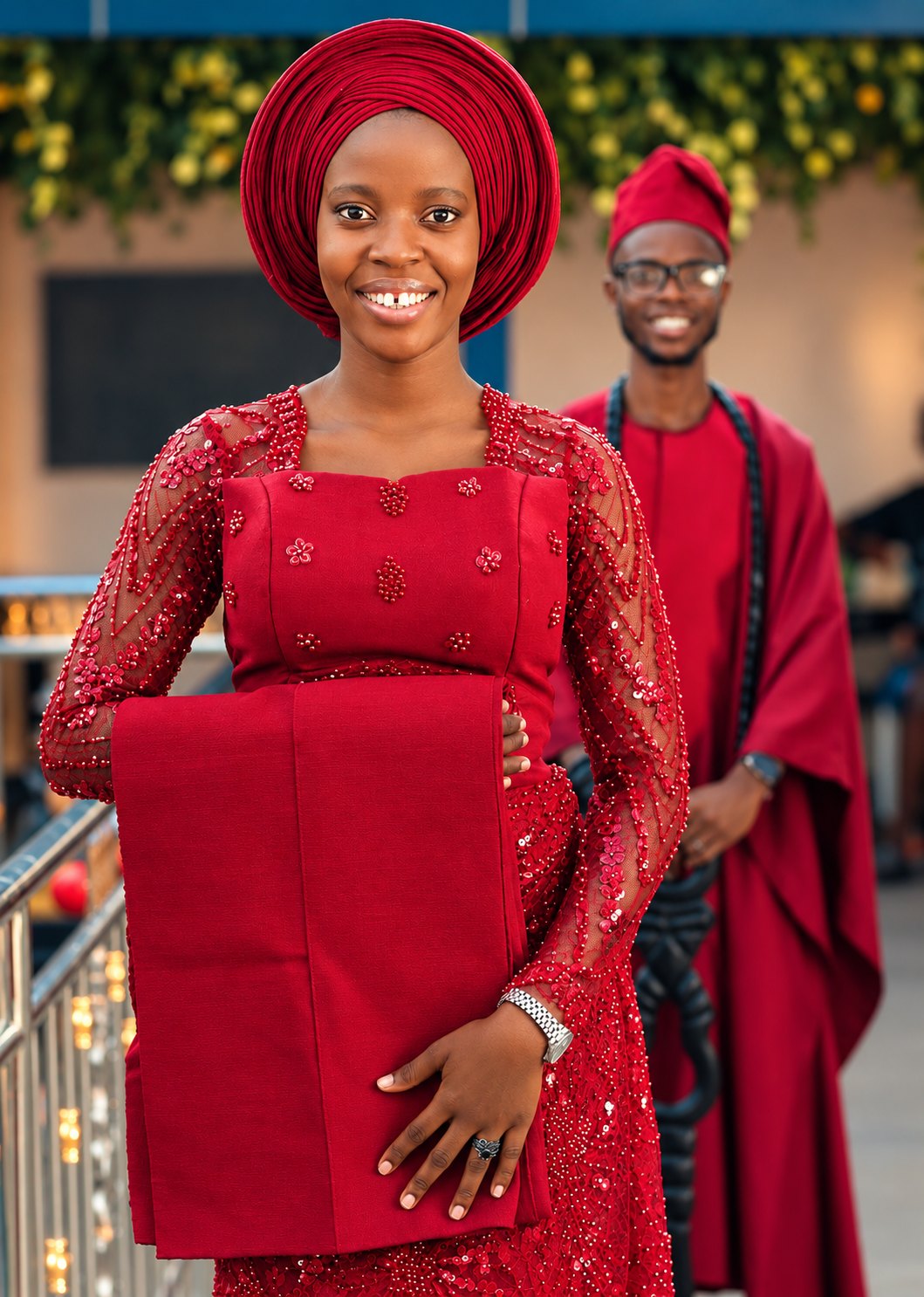 A smiling couple dressed in coordinated red traditional attire